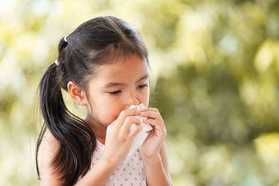 Girl wiping nose with tissue paper