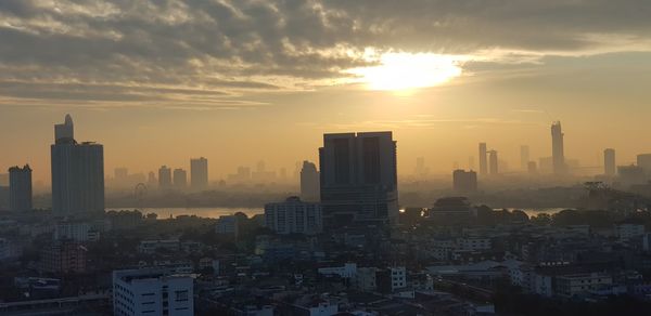 Modern buildings in city against romantic sky at sunset