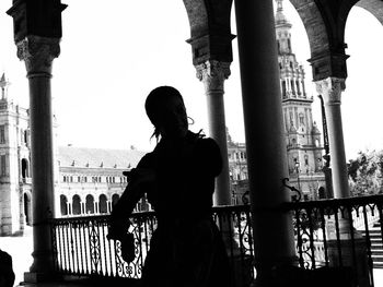 Woman standing by railing against clear sky