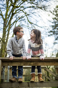 Best friends look at each other while climbing on railing.