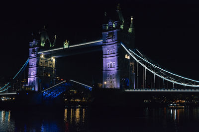 Illuminated bridge over river at night