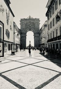 People walking in historic building against sky in city