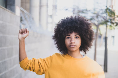 Portrait of beautiful young woman standing against wall