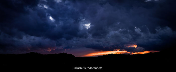 Scenic view of dramatic sky over silhouette mountains