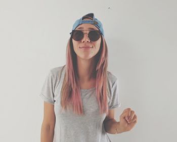 Portrait of young woman wearing sunglasses against white background