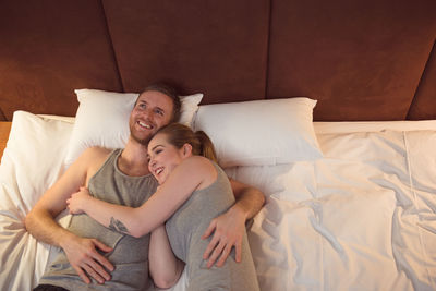 Optimistic man and woman lying on bed