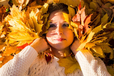 Close-up portrait of young woman with autumn leaves