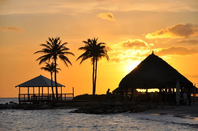 Silhouette palm trees on beach against sky during sunset