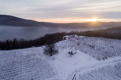 Scenic view of snow covered field against sky during sunset