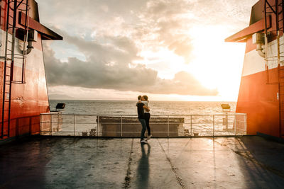 Couple hugging in a boat with a sunset in the background