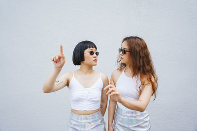 Lesbian couple gesturing while standing against wall outdoors