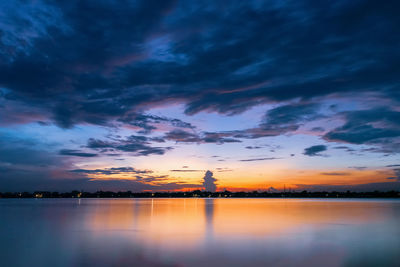 Scenic view of lake against dramatic sky during sunset