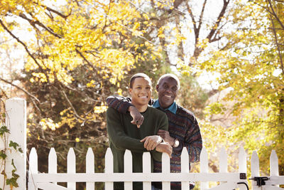 Portrait of father and son standing by fence