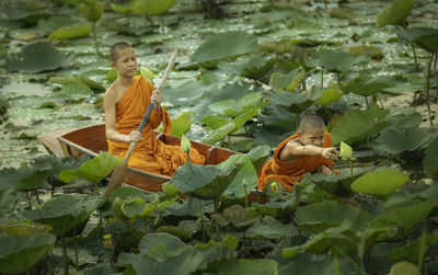 Monks in boat amidst lily pads