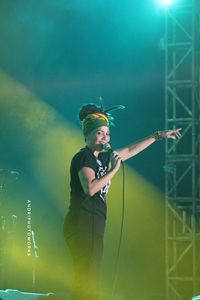 Young man with arms outstretched standing against illuminated light