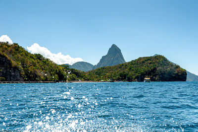 Scenic view of swimming pool by sea against clear blue sky