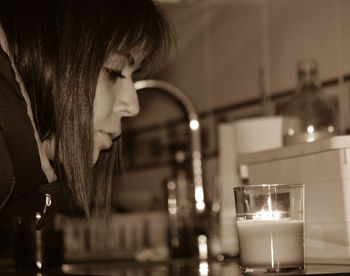 Close-up of woman looking at illuminated candle