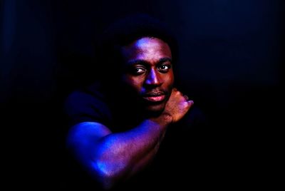 Portrait of young man against black background