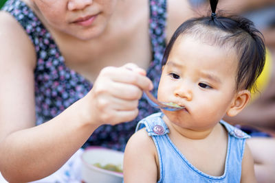 Midsection of mother feeding daughter outdoors