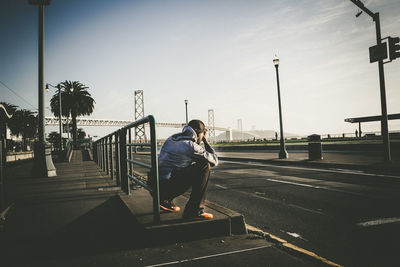 Man photographing on railing against sky