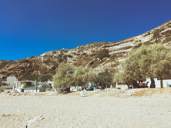 People on sand against blue sky