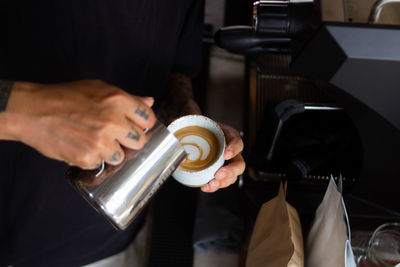 Cropped image of person making cappuccino