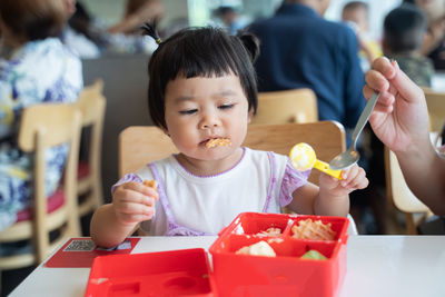 Close-up of girl eating food at restaurant