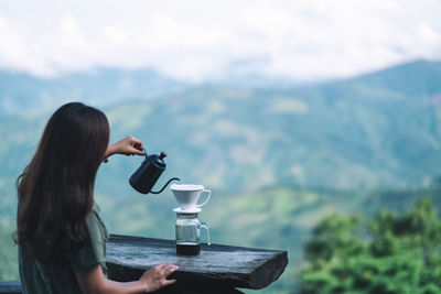 Woman drinking water from coffee in mountains