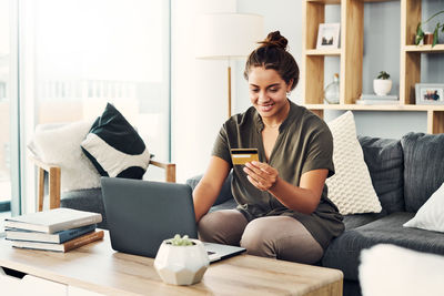 Young woman using phone while sitting on table