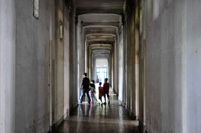 Rear view of people walking in corridor of building