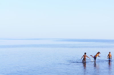 People on sea against clear sky