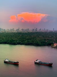 Sunset over chao phraya river with boats and cityscape in background