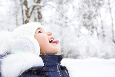 Close-up of girl with mouth open in forest during winter