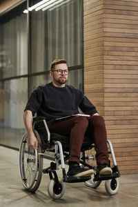 Businessman sitting on wheelchair in office corridor