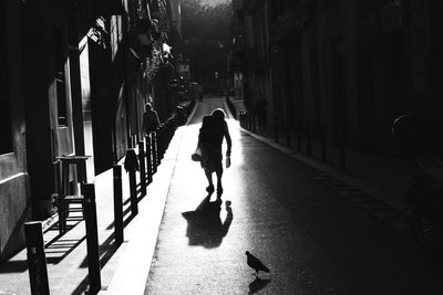 Rear view of man walking on footpath in city