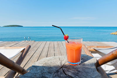 Close-up of drink on table at beach against sky