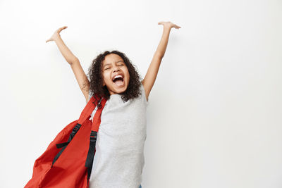 Young woman with arms raised standing against white background