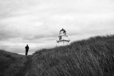 Low angle view of person walking on field by waipapa point lighthouse against sky