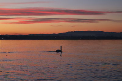 Silhouette person in sea against sky during sunset