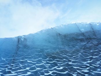 Close-up of icicles on snow against blue sky