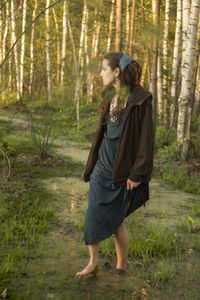 Woman walking in swamp against trees at forest