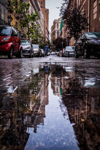 Reflection of buildings on wet road in puddle