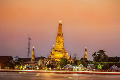 Illuminated buildings in city against sky during sunset