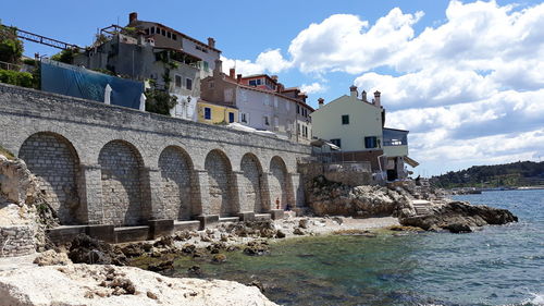 Arch bridge over sea against buildings