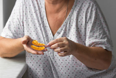 Senior woman's hands holds yellow hydrogel eye patches in front of her, ready for use. health care.