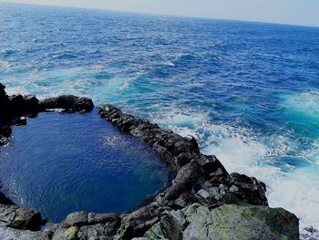 Aerial view of rock formation in sea against sky
