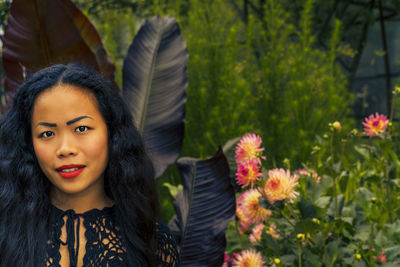 Portrait of beautiful woman standing by flowering plants