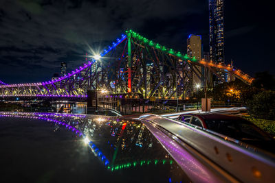 Illuminated bridge over river at night