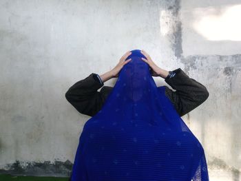 Rear view of woman standing against wall