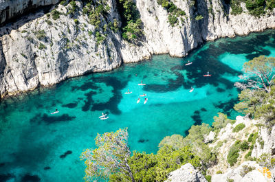 High angle view of people paddleboarding in river between mountain